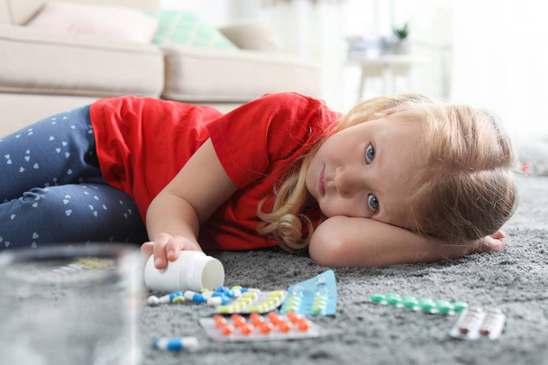 Little child with many different pills on floor at home. Danger of medicament intoxication - Photo, image