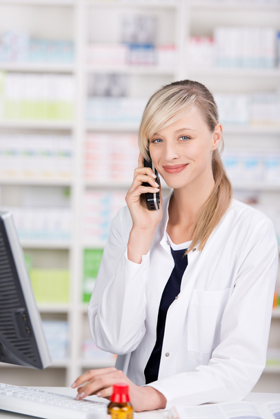 Friendly pharmacist portrait talking at the phone - Photo, Image