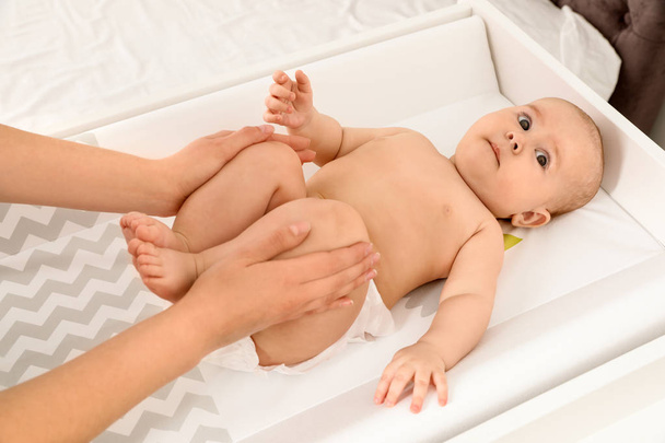 Mother and her cute child on changing table, above view. Baby massage and exercises - Zdjęcie, obraz
