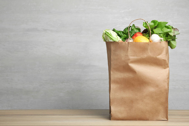 Paper bag with vegetables on table against grey background. Space for text - Φωτογραφία, εικόνα