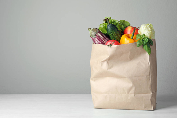 Paper bag with vegetables on table against grey background. Space for text - Photo, image