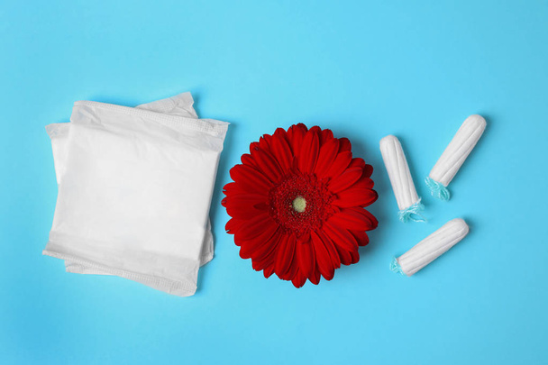 Diferentes produtos de higiene feminina e flor sobre fundo de cor, flat lay. Cuidados ginecológicos
 - Foto, Imagem