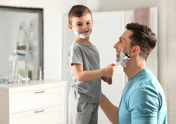 Little son shaving his dad in bathroom - Фото, зображення