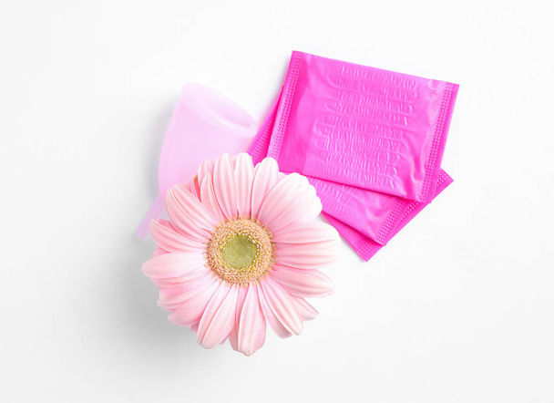 Menstruationspolster und Gerbera-Blume auf weißem Hintergrund, Draufsicht. Gynäkologische Versorgung - Foto, Bild