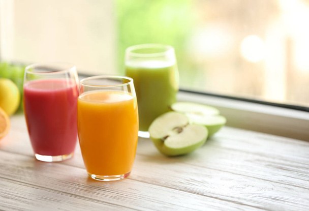 Glasses with different juices and fresh fruits on wooden window sill. Space for text - Fotoğraf, Görsel
