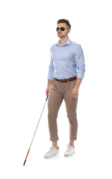 Young blind person with long cane walking on white background - Foto, afbeelding