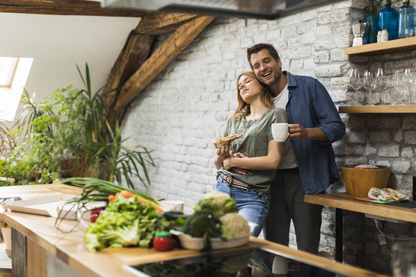 Casal feliz tomando café da manhã juntos na cozinha rústica em casa
 - Foto, Imagem