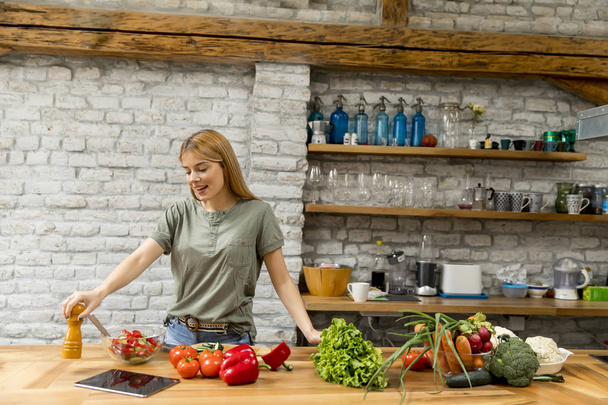 Nuori nainen keittiössä käyttäen tabletin käsittelyssä resepti
 - Valokuva, kuva