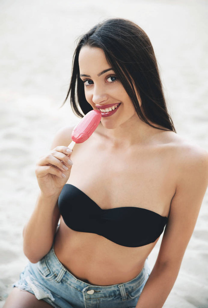 Portrait of young woman  eating ice cream on beach  - Zdjęcie, obraz