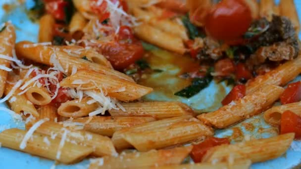 Massa com molho de tomate salgado, carne, parmesão e tomate é comido com um garfo com prato azul. Macarrão é um prato tradicional da cozinha italiana e mediterrânica
. - Filmagem, Vídeo