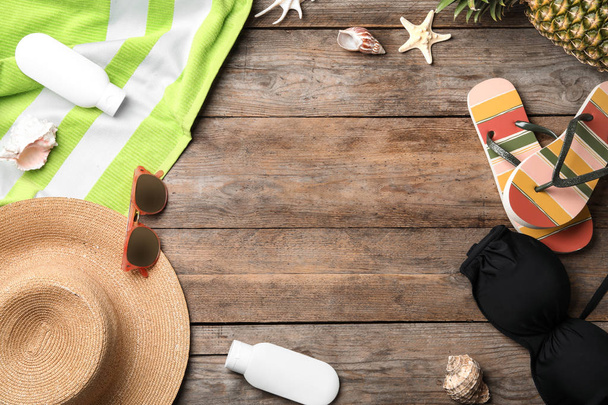 Composición plana con traje de baño y accesorios de playa sobre fondo de madera. Espacio para texto
 - Foto, Imagen
