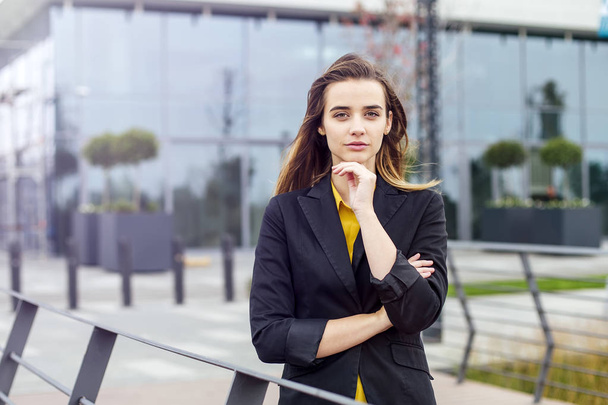 Портрет молодой предпринимательницы, стоящей на открытом воздухе перед зданием компании
 - Фото, изображение