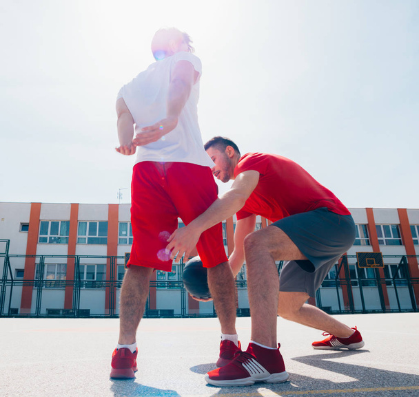 Dos amigos caucásicos con equitación deportiva roja jugando basket
 - Foto, imagen