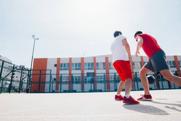 Deux amis caucasiens portant rouge sport equpment jouer panier
 - Photo, image