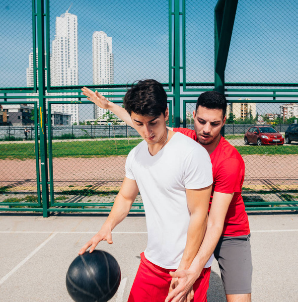 Δύο ισχυροί άνδρες παίκτες μπάσκετ παίζουν μπάλα έξω μάχες  - Φωτογραφία, εικόνα