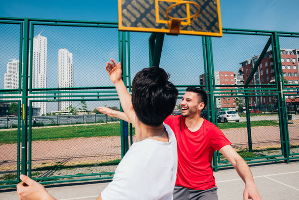 Dos jugadores de baloncesto machos fuertes juegan al aire libre peleando
  - Foto, imagen