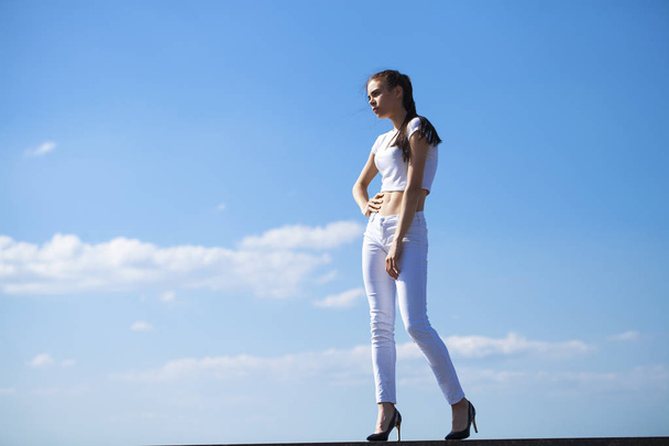 Beautiful brunette woman posing against blue sky bright sunny we - Фото, зображення