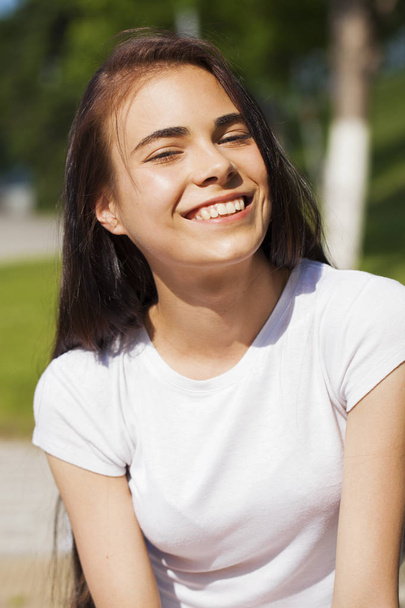 Beautiful brunette woman posing against summer park, bright sunn - Фото, зображення