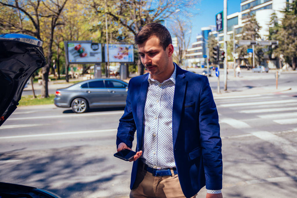 Young businessman is talking on his phone while looking under th - Photo, Image