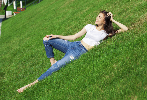 Portrait of a young beautiful girl resting on the lawn in the pa - Foto, Imagem