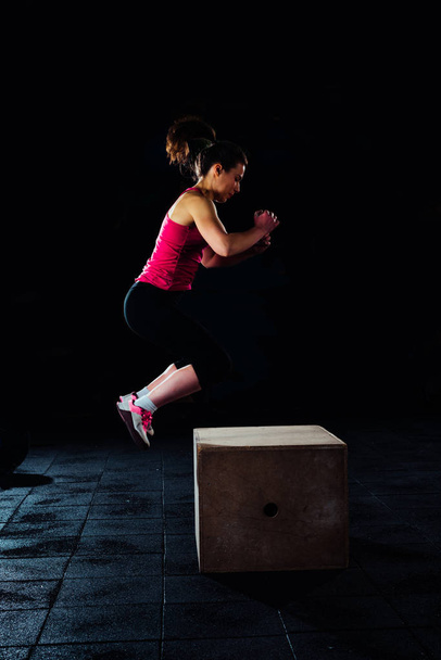 Підходить жінка виконує стрибки коробки в спортзалі
 - Фото, зображення