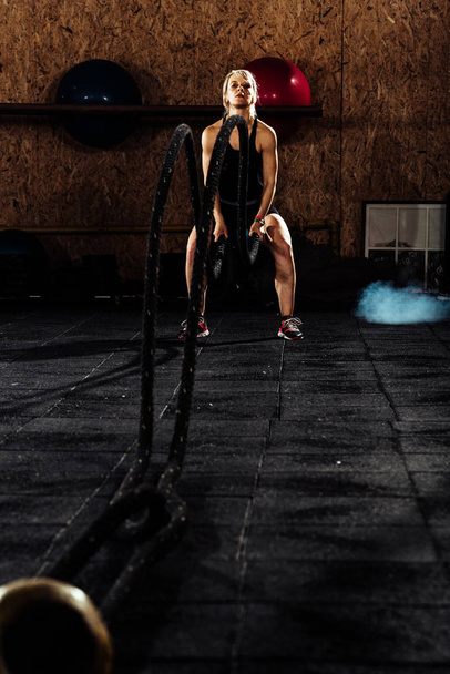 Entschlossene Frau wirft Seile in Turnhalle - Foto, Bild