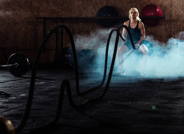 Fitness woman tossing ropes at gym - Foto, Imagem
