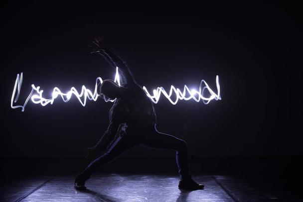 Modern Dance wykonawca taniec z neonowym światłem niebieskim podczas dokonywania łaskawy ruchów i spektakularnych wyrażeń sztuki ciała. - Zdjęcie, obraz