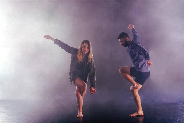 Двоє сучасних танцюристів розтягують ноги високо в ефірі
 - Фото, зображення