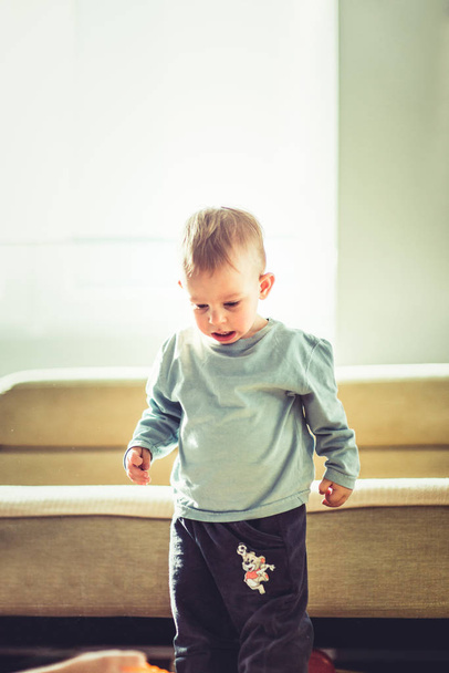 Un bébé garçon se tient debout pour entendre ses jouets et - Photo, image
