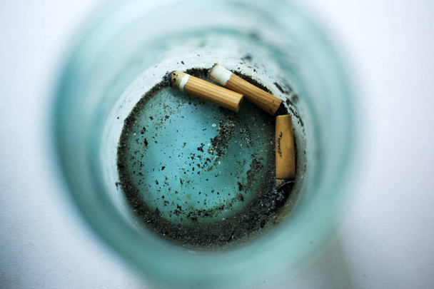 Zigarettenstummel auf dem Boden eines Glasgefäßes - Foto, Bild