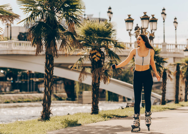 Girl sports and riding roller blading outdoors - Fotó, kép