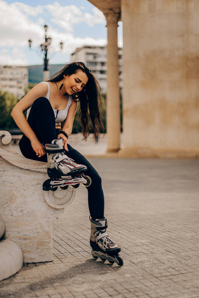 Chica sentada en la pared y pone en patines
 - Foto, imagen