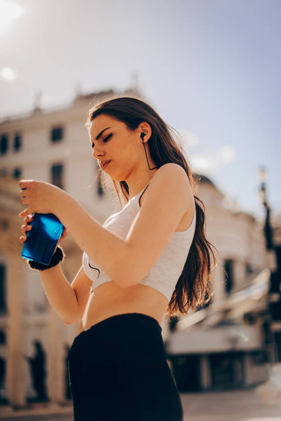 Muscular girl drinking protein shake in urban city - Photo, Image