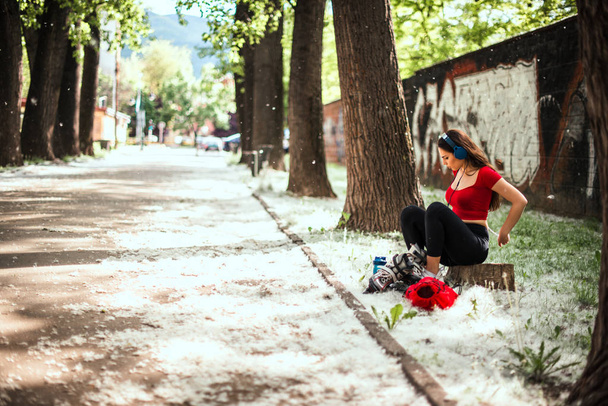 Chica sentada y pone en patines al aire libre
 - Foto, Imagen