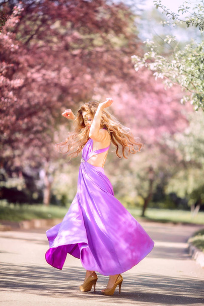 Beautiful young woman in a blossom park - Foto, Imagen