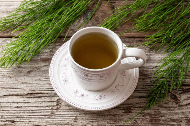 Taze Equisetum arvense bitkisi ile bir fincan at kuyruğu çayı. - Fotoğraf, Görsel
