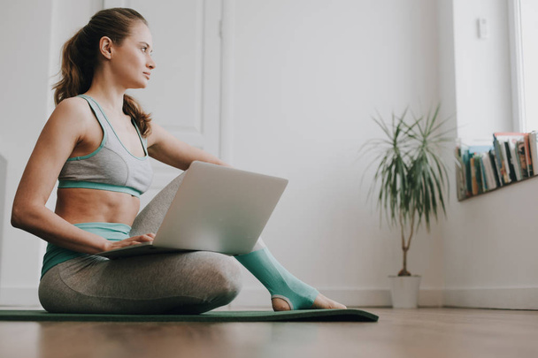 Balanced woman sitting with laptop on bending leg - Foto, Imagen