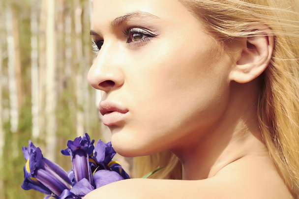 Bella donna bionda con fiori blu nella foresta
 - Foto, immagini