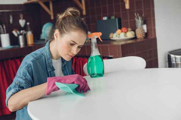 Woman trying to clean table surface at home - Foto, Imagen
