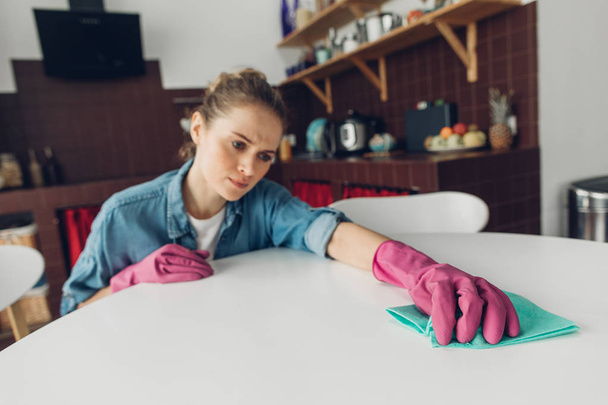 Young female being tired to clean table at home - Fotografie, Obrázek