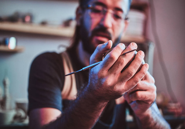 Diligente homem pensativo em óculos em sua oficina de cerâmica é workig para novo projeto
. - Foto, Imagem