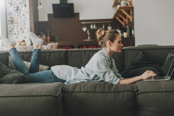 Happy woman laying on couch with laptop - Foto, Bild