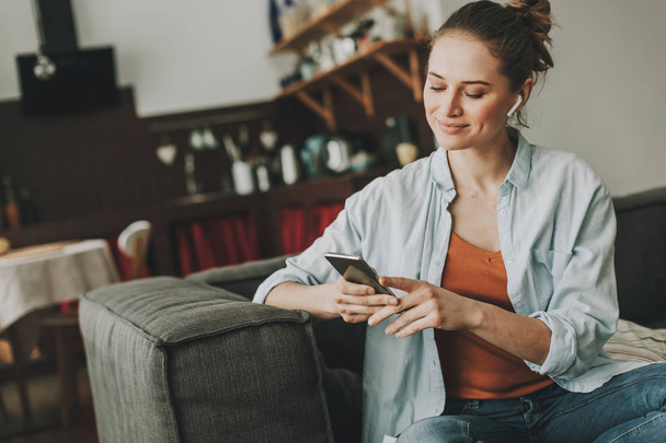 Relaxed lady sitting on sofa with smartphone - Foto, afbeelding