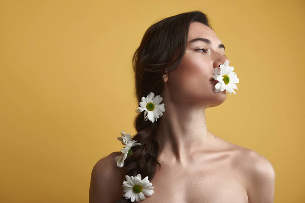 Graceful naked woman holding camomile in mouth - Foto, Imagem