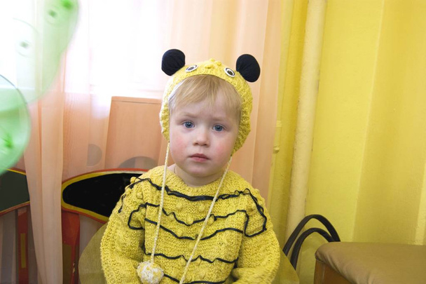 Üç yaşında bir çocuk, mavi gözlü üzgün sarışın bir çocuk, arı kostümü giymiş. - Fotoğraf, Görsel