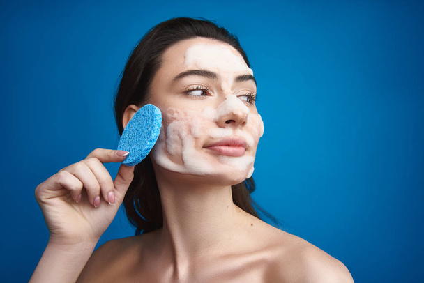 Graseful woman with cosmetic mask and sponge - Foto, Imagen