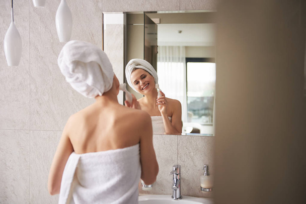 Young lady wrapping in towel cleaning face - Foto, imagen