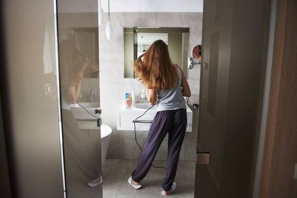 Young lady drying hair by hairdryer in bathroom - Photo, image