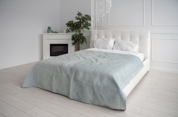 Vue latérale du lit en cuir blanc avec drap de lit bleu et cheminée
 - Photo, image